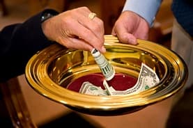 An offering being placed into a gold collection plate